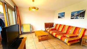 Una sala de estar con un sofá y un televisor de pantalla plana. en Résidence Les Queyrettes - Grand appartement confortable 4/6 personnes MAE-6851, en Puy-Saint-Vincent