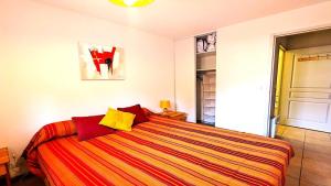 1 dormitorio con 1 cama grande con almohadas rojas y amarillas en Résidence Les Queyrettes - Grand appartement confortable 4/6 personnes MAE-6851, en Puy-Saint-Vincent
