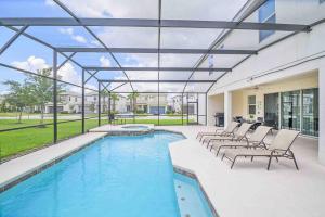 a patio with a pool and lounge chairs and a swimming pool at SUPER SIZE - 11BDr SPACiOUS HOME w POOL & HOT TUB in Kissimmee +30 photos