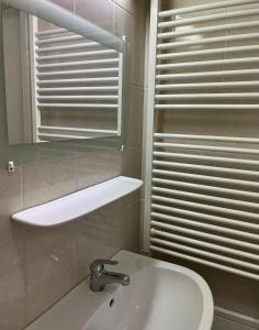 a white bathroom with a sink and a mirror at Aura Apartman in Kecskemét