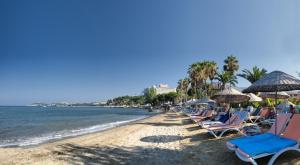 a beach with chairs and umbrellas and the ocean at Ephesia Holiday Beach Club in Kuşadası
