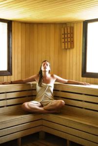 a woman sitting on a bench in a sauna at Ephesia Holiday Beach Club in Kuşadası