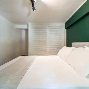 a bedroom with a white bed and a green wall at 4bd Apartment With Outdoor Jacuzzi Garden in Athens