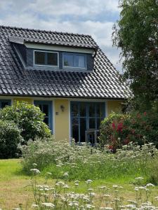 une maison jaune avec un toit gris et des fleurs dans l'établissement Kinderfreundliche Ferienanlage In Idyllischer Lage, à Neuenkirchen