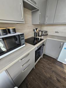 a kitchen with white cabinets and a microwave at Ocean View 2 in Campbeltown