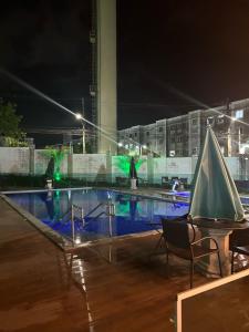 een zwembad 's nachts met een tafel en stoelen bij Villa Natal, cond villa das palmeiras in Jaboatao dos Guararapes