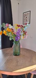 a vase of flowers sitting on a wooden table at De Strandloper Vakantiehuisje aan het strand - Ferienwohnung am Meer in Baarland
