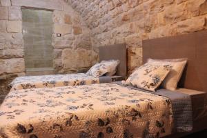 a bedroom with two beds and a stone wall at Aal Aoudeh guesthouse in Dayr al Qamar