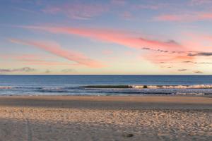 a beach with a sunset and waves in the ocean at Close to the beach #4 Cozy condo in Myrtle Beach