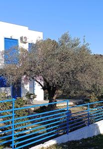 una cerca azul con un árbol delante de un edificio en Haraki Blue Houses, en Charaki