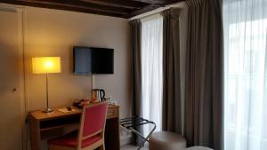 a hotel room with a desk and a tv on the wall at Hôtel Le Compostelle in Paris