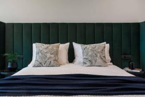 a large bed with a green headboard and pillows at 2 Sidebyside Suites In Athens Riviera By The Olon in Athens