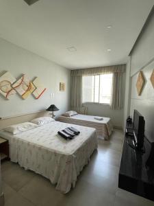 ein Hotelzimmer mit zwei Betten und einem Fernseher in der Unterkunft Flat Praia de Copacabana - Pé na Areia in Rio de Janeiro