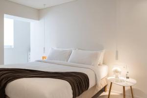 a bedroom with a large white bed with a table at 2bd Boho Sea View Apartment By The Olon in Vari