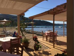 a patio with tables and umbrellas on the beach at Poseidon Garden View Apartment in Perivólion
