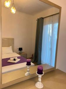 a mirror reflecting a bedroom with purple hats on a bed at Poseidon Garden View Apartment in Perivólion