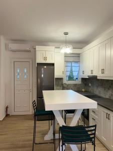 a kitchen with white cabinets and a table and chairs at Poseidon Garden View Apartment in Perivólion +29 photos