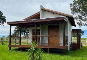 a small house with a balcony in a field at Chalés da Marisa - Serra da Canastra in São João Batista do Glória