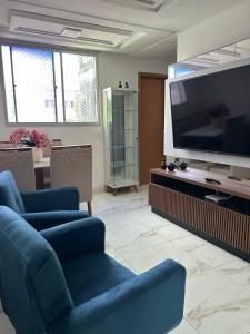 een woonkamer met een blauwe bank en een flatscreen-tv bij Villa Natal, cond villa das palmeiras in Jaboatao dos Guararapes