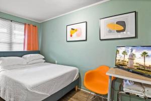 una camera da letto con un letto e una scrivania con una televisione di Dive into the 50s- Restored Motel in St Augustine a St. Augustine