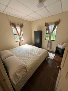 a bedroom with a large bed and two windows at Casa de Campo in Santa Cruz Verapaz