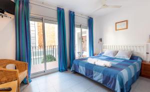 a bedroom with a bed with blue curtains and a balcony at Hola Sitges Apartments in Sitges