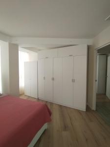 a bedroom with white cabinets and a red bed at Bonito departamento en cercado in Tacna
