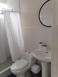 a white bathroom with a toilet and a sink at Bonito departamento en cercado in Tacna