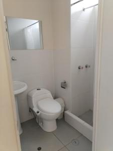 a white bathroom with a toilet and a sink at Bonito departamento en cercado in Tacna