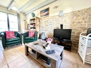 a living room with a stone wall and a tv at Ty Chouette Cottage, proche Lac, Nature in Priziac