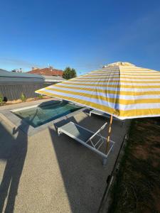 a yellow and white umbrella sitting next to a pool at California 'Luxe Boho' with Pool in Echuca