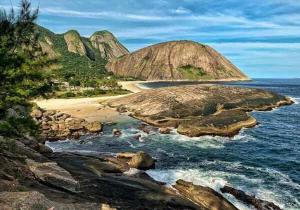 a view of a beach with rocks and the ocean at Pousada por do sol in Niterói