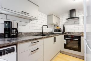 a kitchen with white appliances and white tiles at Ashton Getaway Sleeps 14 Free Parking in Dukinfield