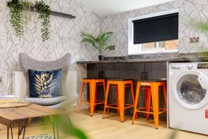 a living room with a washing machine and orange stools at Ashton Getaway Sleeps 14 Free Parking in Dukinfield