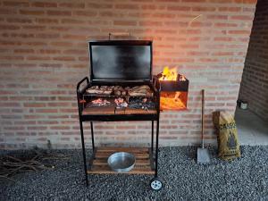 a grill with food on it next to a brick wall at Los Chivos in Villa Cura Brochero