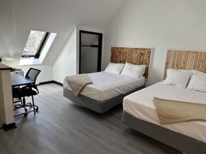two beds in a room with a desk and a table at Harborside Suites in Yarmouth