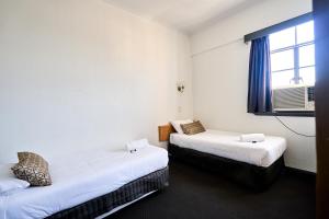 two beds in a small room with a window at Beer Deluxe Albury in Albury