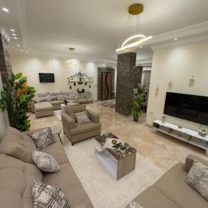 Hotel Apartment In Sheikh Zayed With Private Entrance في Sheikh Zayed: غرفة معيشة كبيرة مع كنب وتلفزيون بشاشة مسطحة
