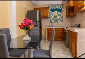 a kitchen with a table with a vase of flowers on it at Scenic 3 Bedroom Apartment And Car Rentals in Canefield
