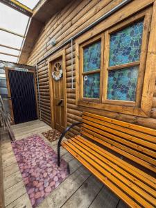 un banco de madera sentado frente a un edificio con ventanas en Cabaña Aquiles, en Puerto Natales