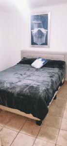 a bed with a black comforter in a room at Salón y habitaciones in San Patricio