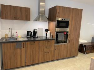 a kitchen with wooden cabinets and a sink and a microwave at Gîte Le Cottereau , à 5 minutes du Zoo Parc de Beauval in Seigy +32 photos