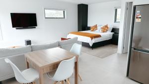 a living room with a couch and a table and a bed at Views on Sapphire - Brand New - Adults Only in Merimbula