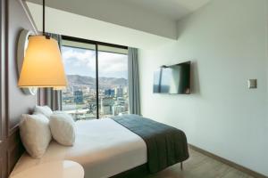 a hotel room with a bed and a large window at Studio 56 by Terrado in Antofagasta