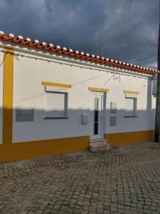 a white and yellow house with a cobblestone street at Casinha de Galveias in Galveias