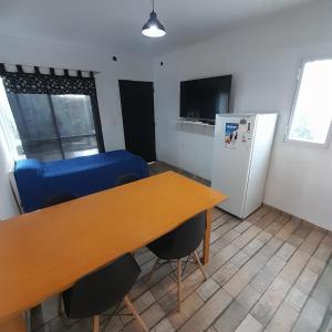 a room with a table and a blue couch and a refrigerator at Complejo Lua in Villa Cura Brochero