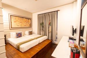 a bedroom with a bed and a desk and a television at Pukha Nanfa Hotel in Nan