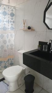 a bathroom with a white toilet and a sink at Vila Negreiros Serra Negra Casa 3 in Bezerros