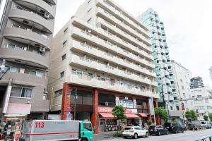 un grand bâtiment dans une rue de la ville avec des voitures dans l'établissement Yuina Hotel Shinjuku, à Tokyo