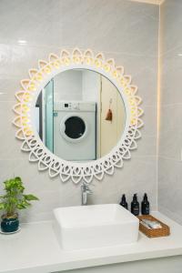 a bathroom mirror with a sink and a washing machine at BRIO Hotels & Apartments in Da Nang